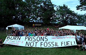 people in a field with banner: "Burn Prisons not fossil fuels"