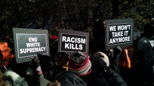 Protesters with signs saying Racism Kills & We Won't take it anymore