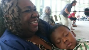 Photo of Delores Winston throwing her head back and laughing after she's just graduated from Seattle Central Community College, her grandson's head resting on her.