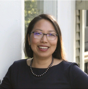 woman with glasses smiles into camera