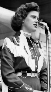 A female country singer wearing a traditional western outfit and singing into a microphone