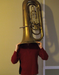 photo of person with tuba inverted over the head